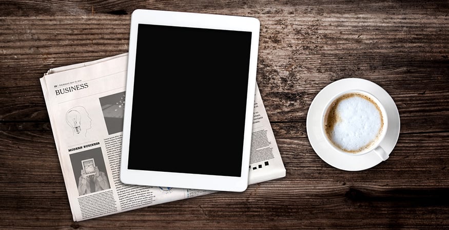 Sanomalehti, tablet-tietkone ja kahvi pöydällä
